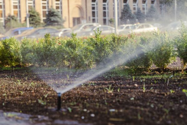 Irrigation sprinklers in parking lot garden outside of office building